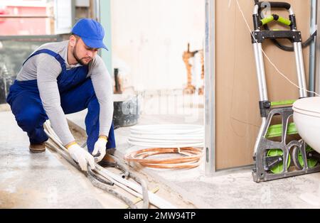 Man electrical installer laying cables through trench Stock Photo