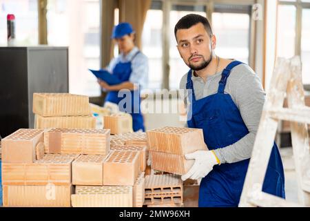 Repairman carrying bricks in construction site Stock Photo
