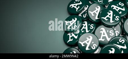 Logos of the American Major League Baseball Team Oakland Athletics on a heap on a table. Stock Photo