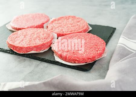 Burger patties close-up. Fresh raw burger patties close-up on a grey stone background, copy space Stock Photo