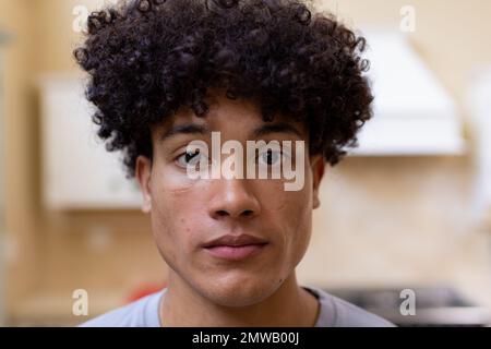 Portrait of biracial man with curly hair in kitchen at home Stock Photo