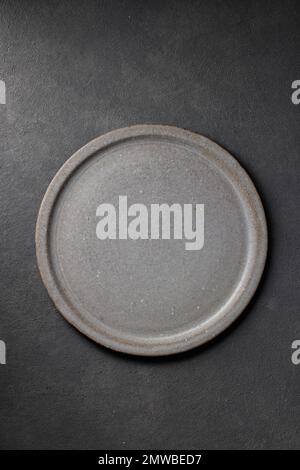 empty ceramic plate on dark grey table background, top view Stock Photo