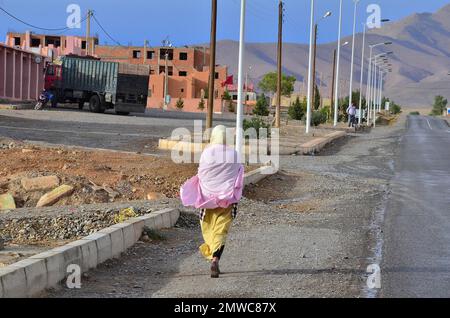 Woman walking on pavement in front of new housing estate under construction, Morocco Stock Photo