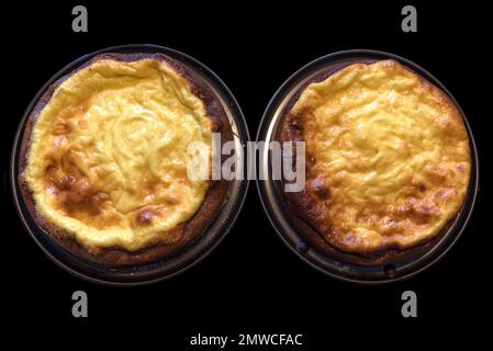 Two freshly baked small cheesecakes in the baking tin on a black background, Bavaria, Germany Stock Photo