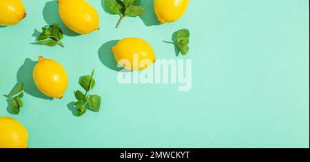 Fresh yellow lemons with mint on minimal blue background on bright sun light with hard shadows pattern summer background flat lay from above, citrus Stock Photo