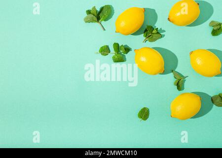Fresh yellow lemons with mint on minimal blue background on bright sun light with hard shadows pattern summer background flat lay from above, citrus Stock Photo