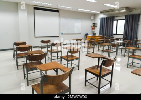 A school classroom with many wooden chairs well-arranged in rows with no student Stock Photo