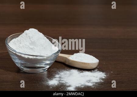 Baking soda - glass bowl and wooden spoon with baking soda; on dark wooden background. Stock Photo