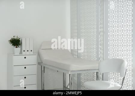 Examination room with modern couch and folding screen in clinic Stock Photo