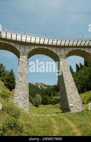 A vertical low-angle shot of the Spiral viaduct and its surrounding greenery in Brusio, Switzerland Stock Photo