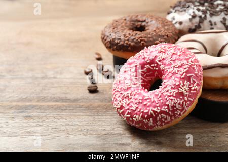 Yummy donuts with sprinkles on wooden table, closeup. Space for text Stock Photo