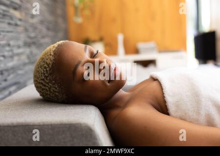 Happy african american woman wearing towel, lying with eyes closed Stock Photo