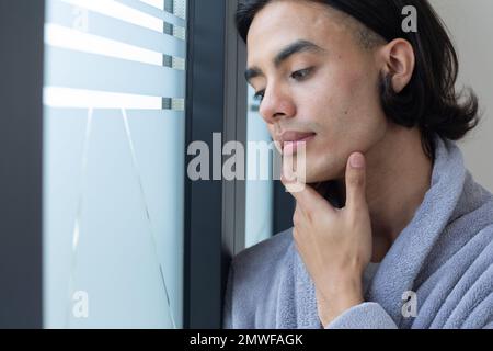 Biracial man looking through window Stock Photo