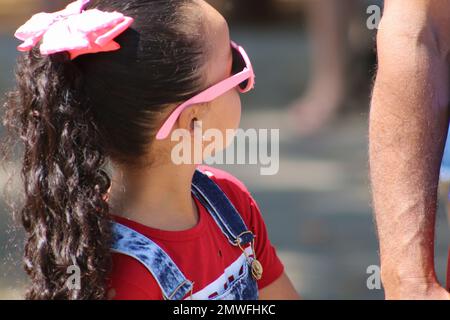 Little girl wearing glasses looking up at the adult walking along with her. Stock Photo