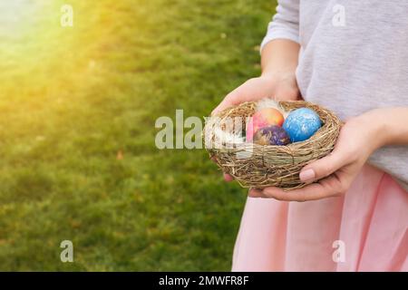 Woman holding nest with Easter eggs outdoors Stock Photo