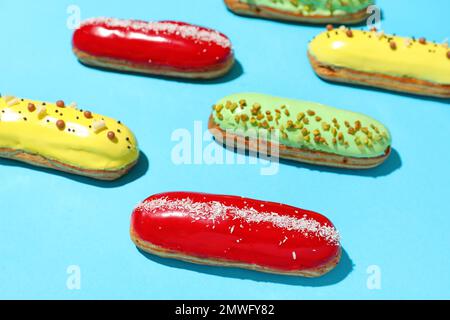 Composition with delicious eclairs on blue background Stock Photo