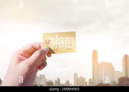 Close up of male hand holding credit card on blurred cityscape background, Shopping and travel concept Stock Photo