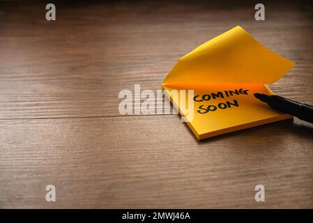 Coming soon written on a yellow paper with a black marker pen. Stock Photo