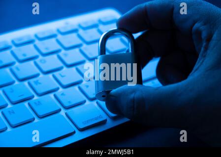 Computer security concept. Hand holding padlock on laptop keyboard.Computer is protected from online cybercrime and hacking Stock Photo