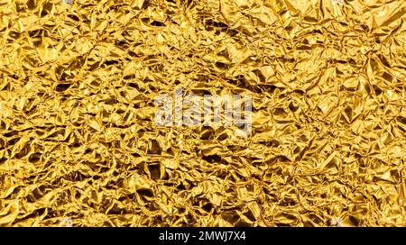 Bright yellow texture of crumpled and creased gold foil or leaf for background. Stock Photo