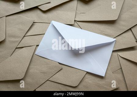 A white envelope on a stack of brown craft envelopes. Stock Photo