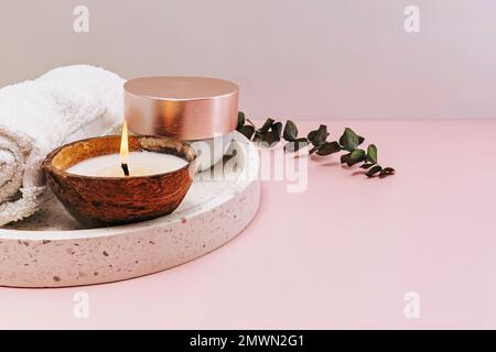 Still life body and face care items and candle in coconut shell on pink background Stock Photo