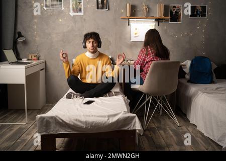 Student meditating on bed in college dorm room. Copy space Stock Photo