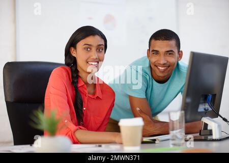 They make a great team. Portrait of two young designers working together at a computer. Stock Photo