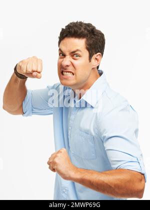 Losing his cool. An angry young man with fists clenched ready to punch against a white background. Stock Photo