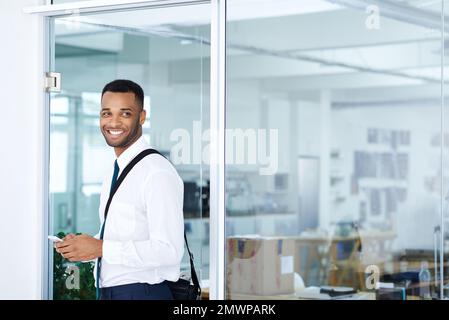 Feeling relaxed in his office. A handsome young african american businessman using his smartphone while in the office. Stock Photo