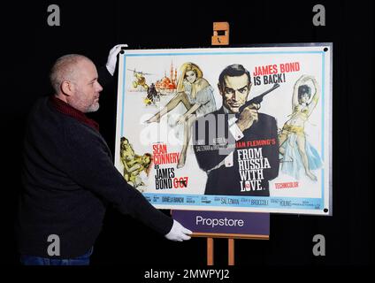 Propstore poster consultant Mark Hochman adjusts a UK quad poster for the 1963 James Bond film 'From Russia With Love' (Estimate £8000 - £16,000) during a preview for the showbiz memorabilia auction, at the Propstore in Rickmansworth, Hertfordshire. Picture date: Thursday January 19, 2023. Stock Photo