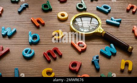 Scattered colorful alphabet with a magnifying glasses. Learning and education concept. Finding keywords. Language learning. Stock Photo