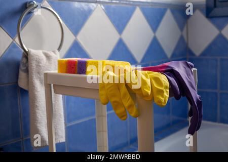 Rubber gloves and sponges on white shelf inside bathroom. Set of colorful accessory for house cleaning. Clean house Stock Photo