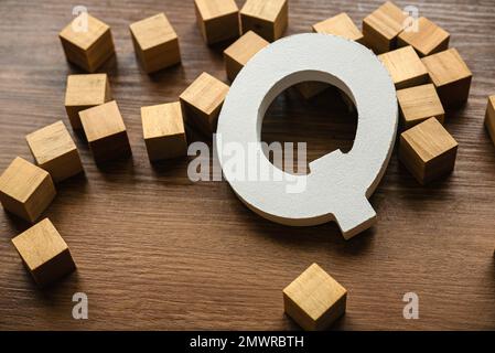 Wooden letter Q on a brown wooden background. Stock Photo