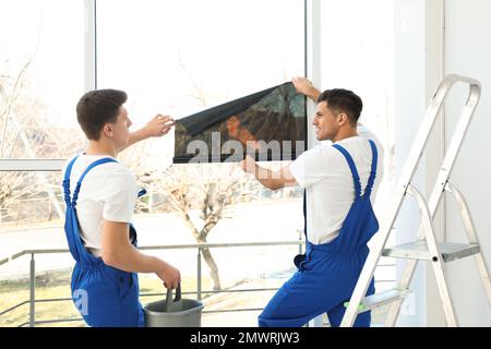 Professional workers tinting window with foil indoors Stock Photo
