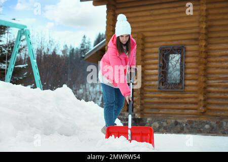 Woman cleaning snow with shovel outdoors on winter day Stock Photo