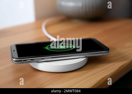 Smartphone charging on wireless pad in room Stock Photo