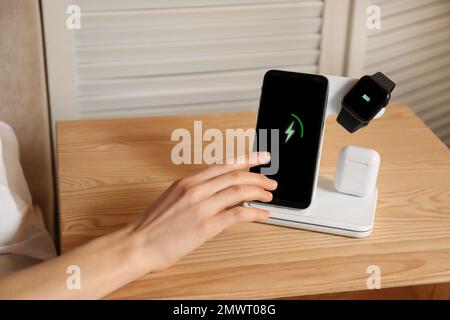 Woman taking smartphone from wireless charger in bedroom, closeup Stock Photo