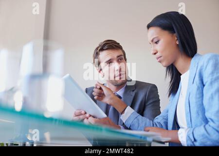 Business strategizing aided by technology. two business executives discussing work on a digital tablet. Stock Photo