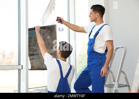 Professional workers tinting window with foil indoors Stock Photo