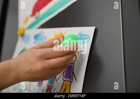 Woman putting child's drawing on refrigerator, closeup Stock Photo