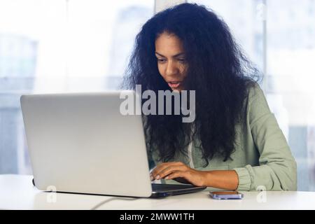 Young black woman works on laptop at home. Freelancer BIPOC female doing distant work online Stock Photo