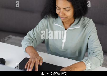 Female programmer coding on notebook pc at home. Portrait of black woman typing text on laptop keyboard with a smile Stock Photo