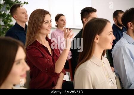 Woman raising hand to ask question at business training indoors Stock Photo