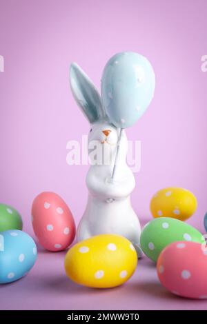 Easter bunny figure and dyed eggs on violet background Stock Photo
