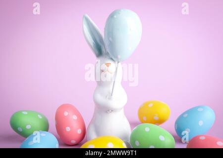 Easter bunny figure and dyed eggs on violet background Stock Photo