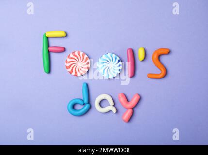 Flat lay composition with words FOOL'S DAY on violet background. April holiday Stock Photo