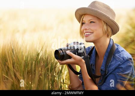 Photographing the beauty of nature. An attractive young woman holding a camera while crouched beside copyspace in a field. Stock Photo