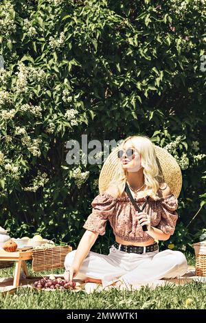 Photo of a charming pretty cute blonde lady who is holding a strawberry in her hand. Outdoor recreation,summer picnic. Stock Photo