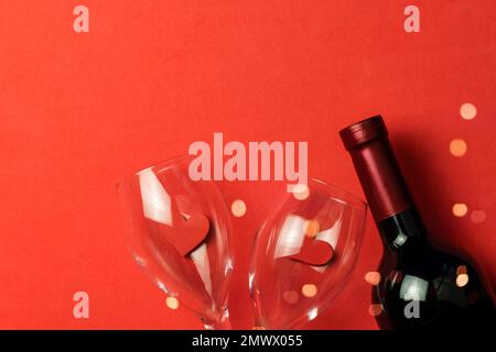 Bottle of wine, glasses hearts on a red background with copy space, top view. Concept of Valentine's day, love, festive dinner Stock Photo